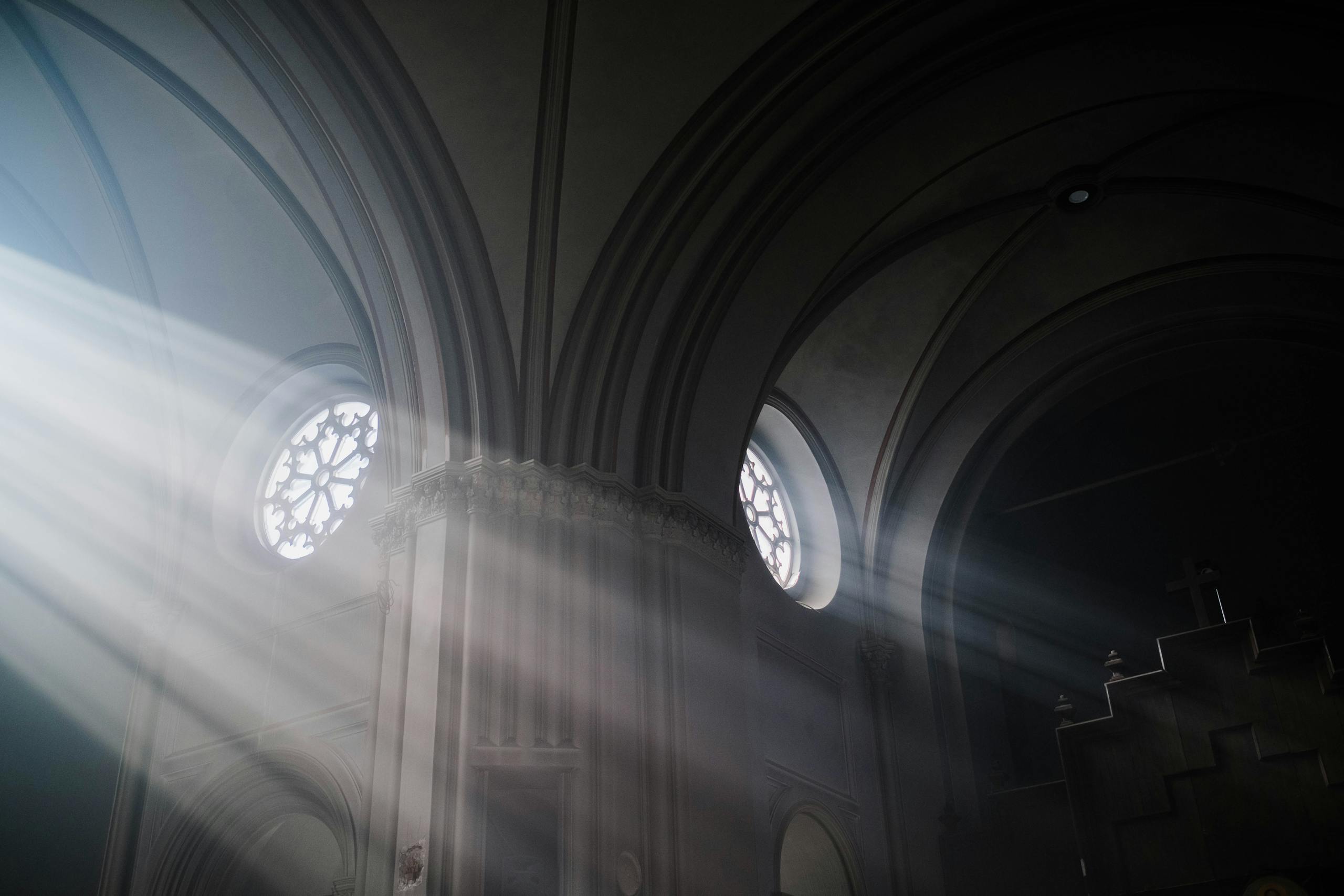 Atmospheric church interior with sunrays highlighting the architecture and stained glass windows.